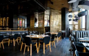 Salle de restaurant avec tables dressées, lumière tamisée et sièges en cuir, illustration pour choisir un restaurant en Suisse