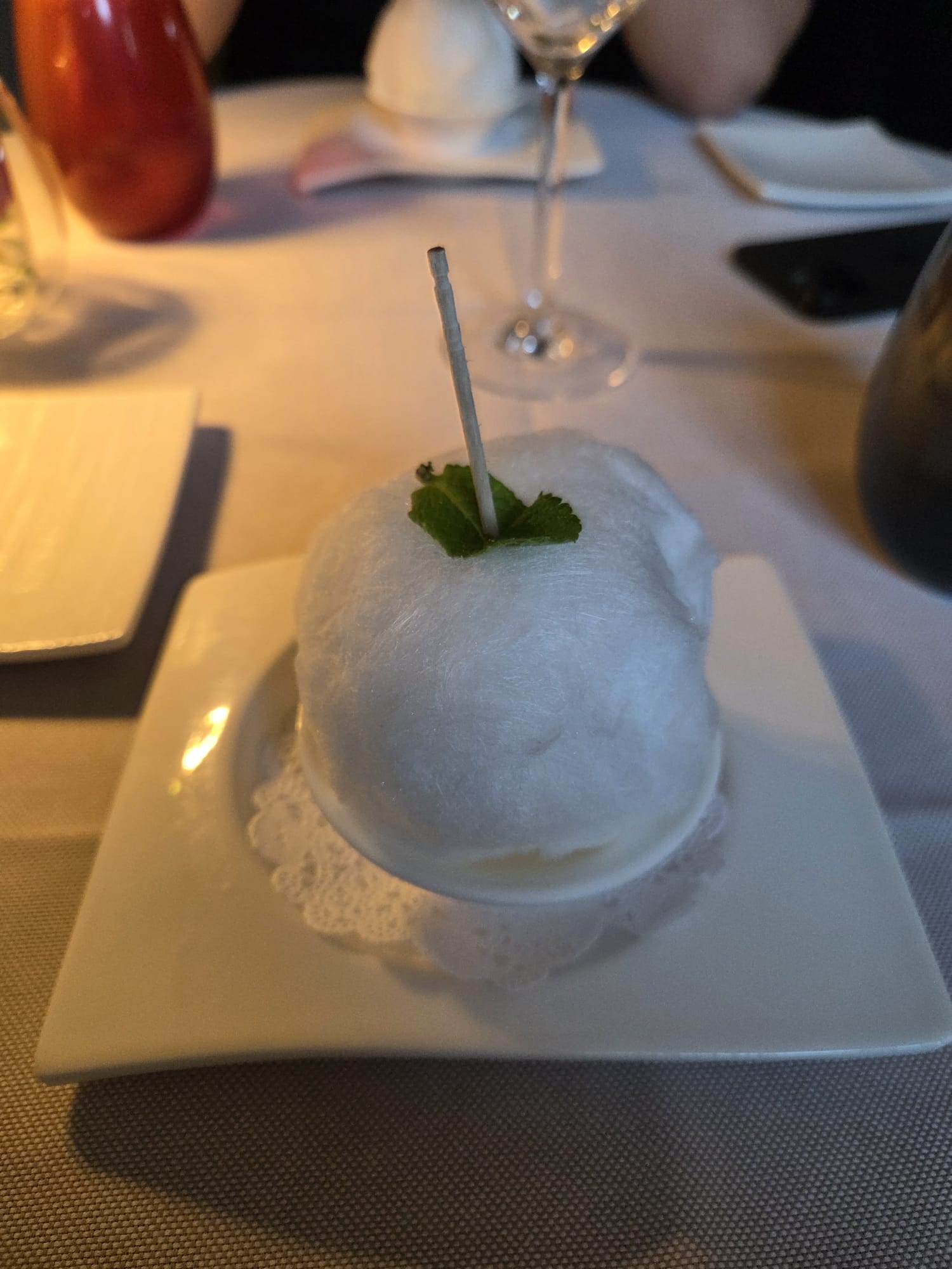 Dessert surprise enveloppé dans une barbe à papa blanche, feuille de menthe et bâtonnet de sucre au Restaurant Guillaume Tell Lavaux