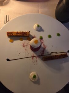 Dessert red velvet décomposé en plusieurs éléments sur assiette blanche, chantilly, points de coulis mangue et herbe, biscuits dorés au Restaurant Guillaume Tell Lavaux