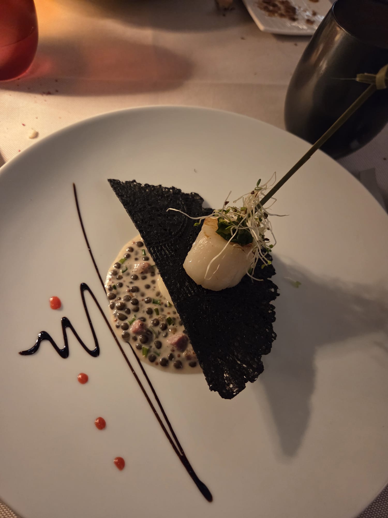 Noix de Saint-Jacques snackée sur brochette, lentilles beluga crémées et tuile dentelle à l'encre de seiche au Restaurant Guillaume Tell Lavaux